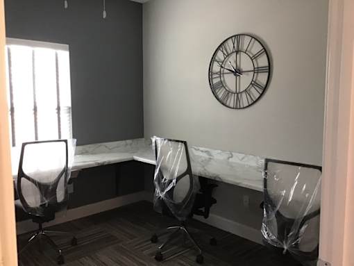 Three chairs are covered in plastic and placed in front of a marble bench.