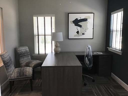 A room with a chair, a table, and a painting on the wall.