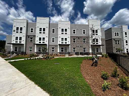 an exterior view of an apartment building with a man walking in the yard