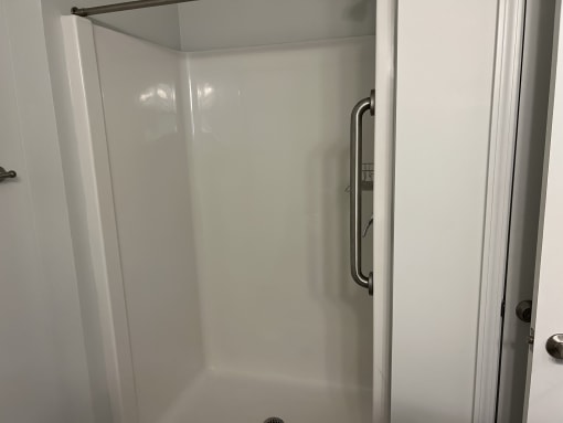 a shower with a shower handle in a small bathroom