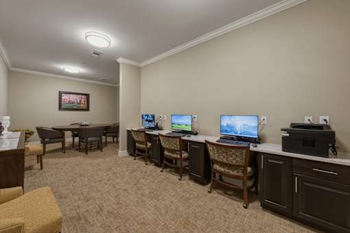 A room with a desk, chairs, and computers.