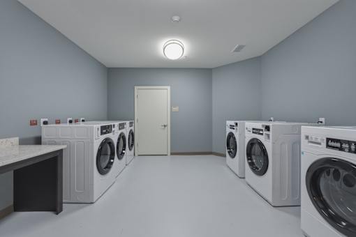 A row of washing machines are lined up in a laundry room.