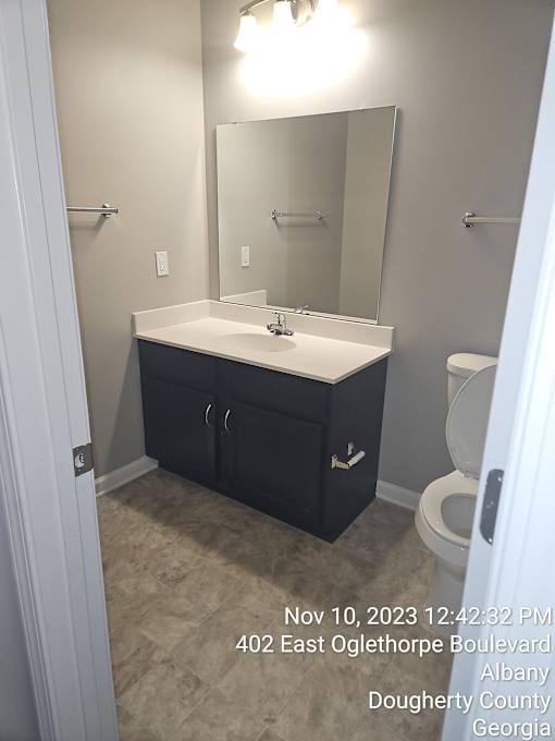 A bathroom with a toilet, sink, and mirror.