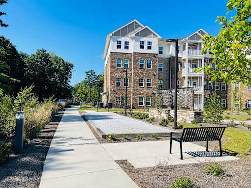 A black bench sits on a concrete slab in front of a building.