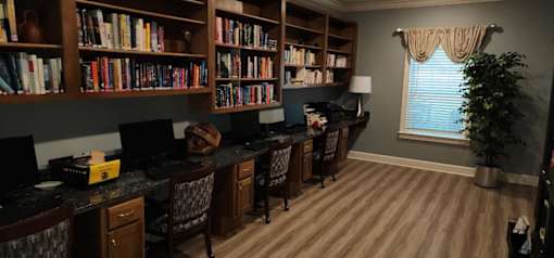 A room with a desk and chairs and two maps on the wall.