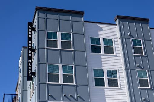 The Carrington Manor building has a grey and white exterior.