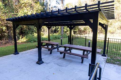 A black pergola with a picnic table underneath it.