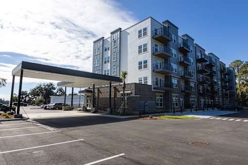 A large parking lot in front of a modern apartment building.