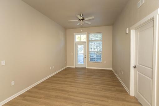 A room with a ceiling fan and a door leading to a balcony.