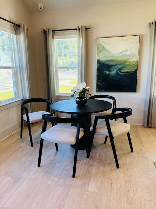 A black table with four chairs and a painting on the wall.