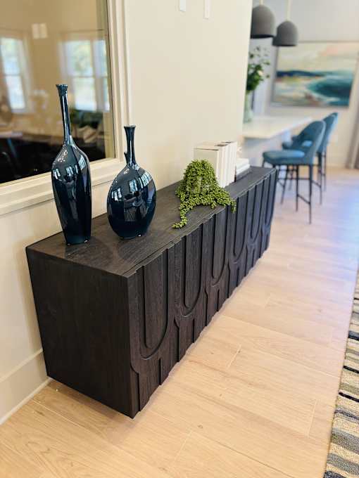 A black wooden bench with three vases on it.