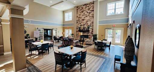 A large room with tables and chairs and a stone fireplace.