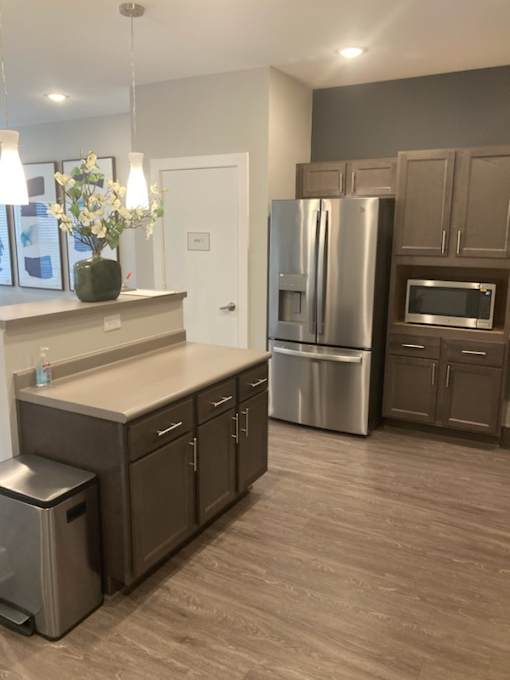 A kitchen with a refrigerator, microwave, and oven.