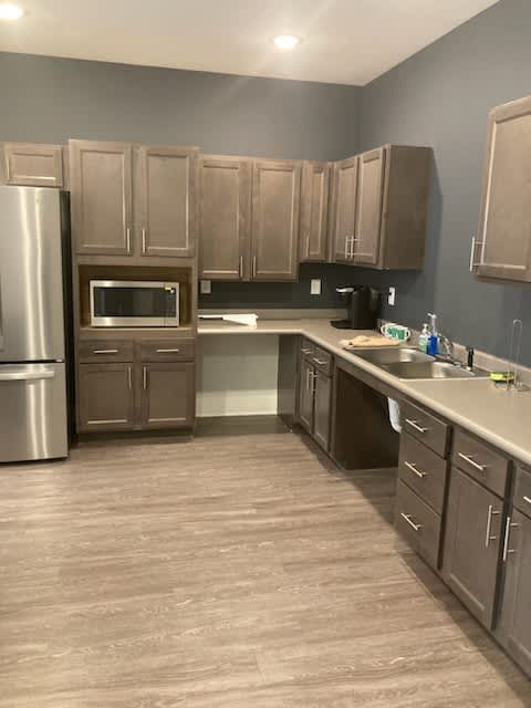 A kitchen with wooden cabinets and a stainless steel refrigerator.
