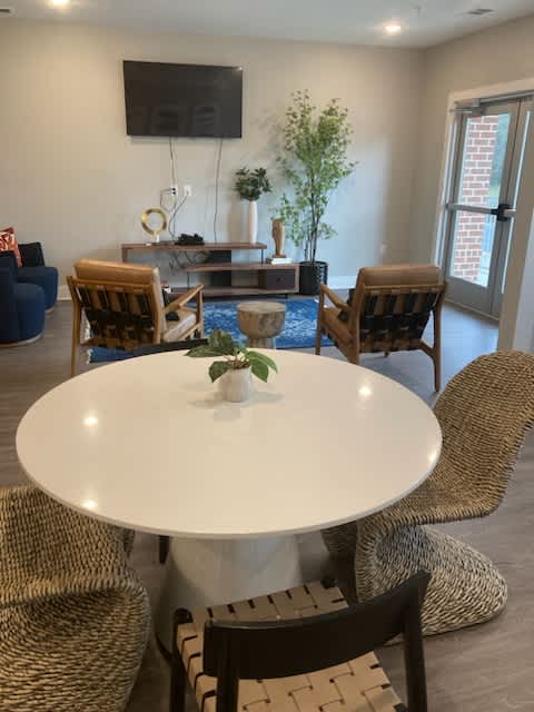A white table with a vase on it and chairs around it.