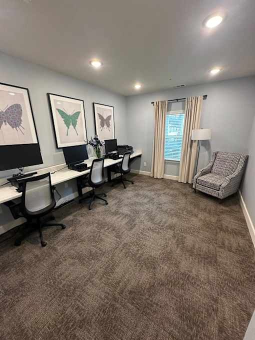 A room with a carpeted floor and a desk with chairs.