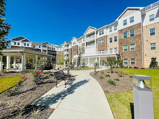 A sunny day at a residential complex with a walkway and a bench.