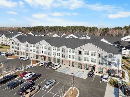 A parking lot in front of a building with cars parked.