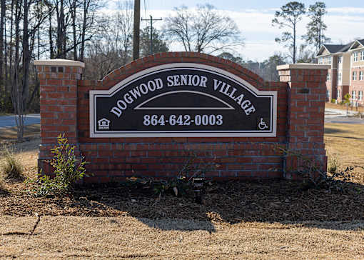 A sign for Dogwood Senior Village with a phone number on it.