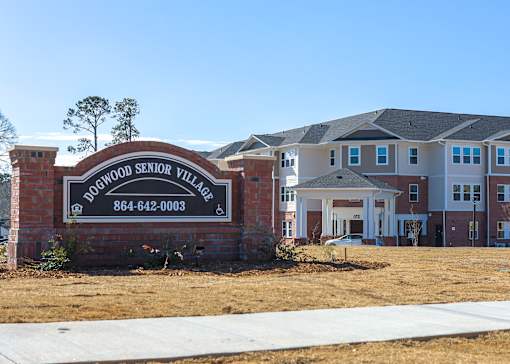 A sign for Woodland Senior Village with a phone number on it.