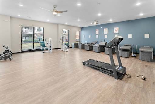 A spacious gym with a treadmill, exercise bikes, and other equipment.