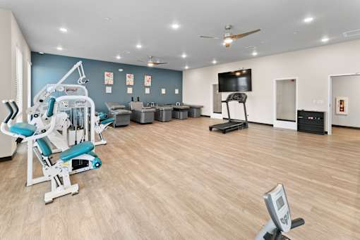 A gym with a variety of equipment including a treadmill, weights, and a bench press.