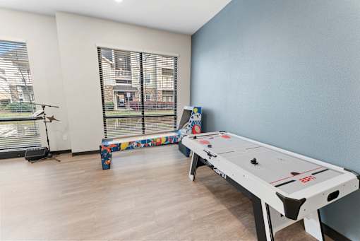 A shiny air hockey table sits in a room with a window and a bench.