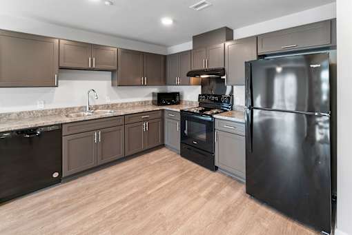 A kitchen with a black refrigerator, black oven, and black dishwasher.