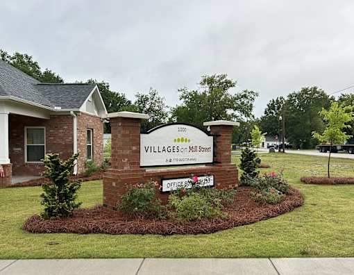 A sign for Villages on Mill Street is in front of a house.