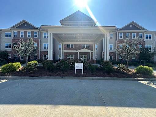 A sunny day at a large, multi-story residential building with a driveway in front.