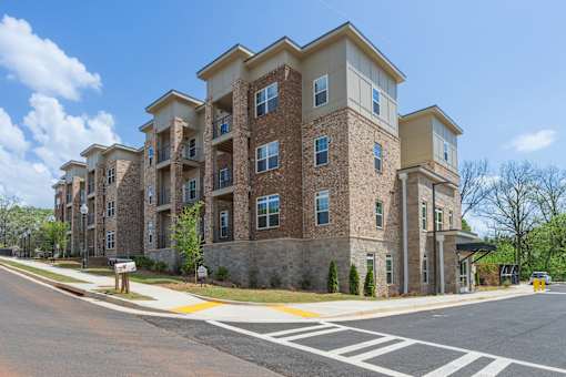 A large apartment building with a stone facade and multiple balconies.