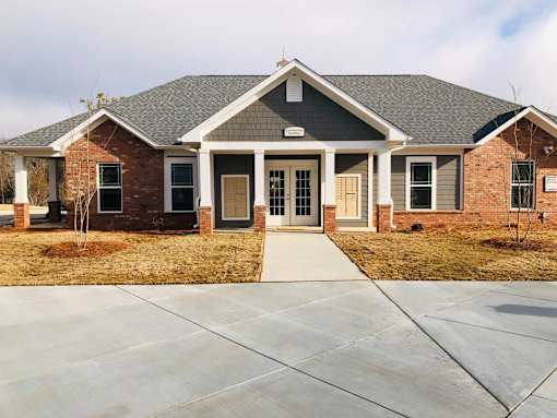 A brick house with a grey roof and a concrete driveway.