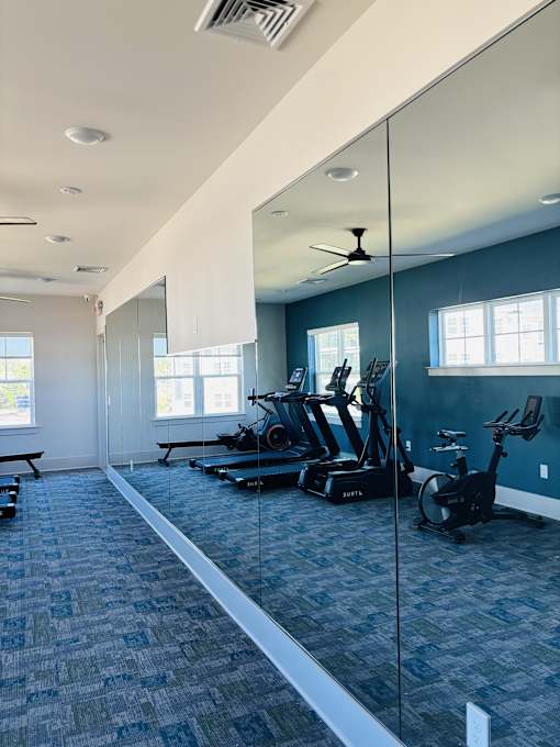 A gym with a mirrored wall and exercise equipment.