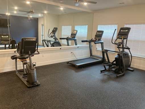 A gym with treadmills, elliptical machines, and a mirror.