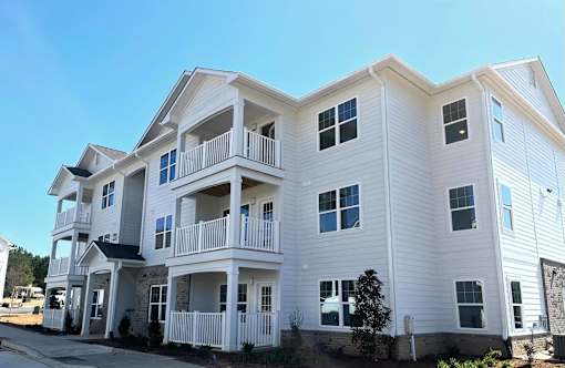 A white two-story apartment building with balconies and multiple windows.