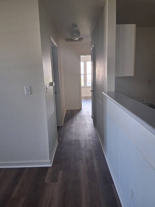 A long hallway with wood floors and white walls.