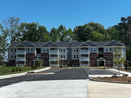 A large apartment complex with a parking lot in front.