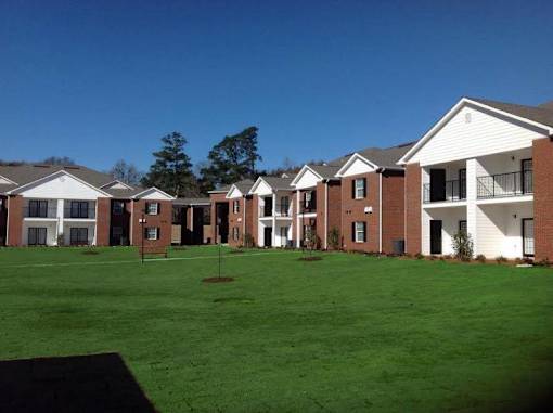 A row of houses with a green lawn in front.
