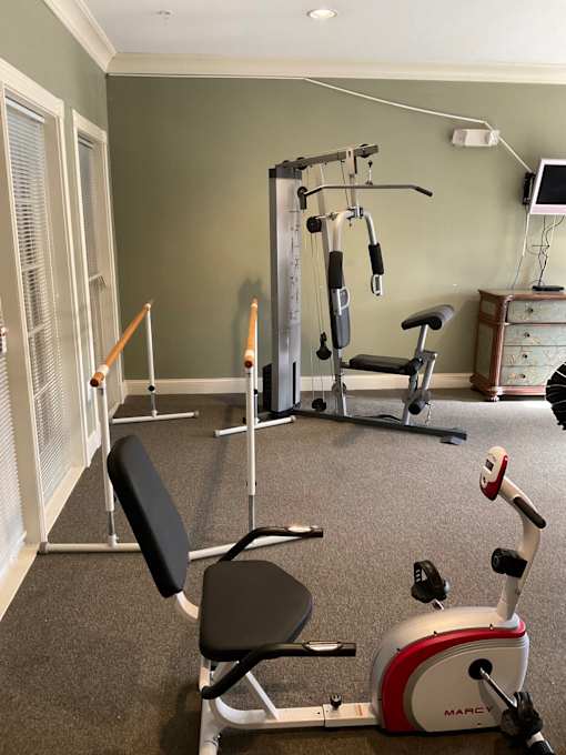A home gym with a variety of equipment including a weight machine, a bench press, and a treadmill.