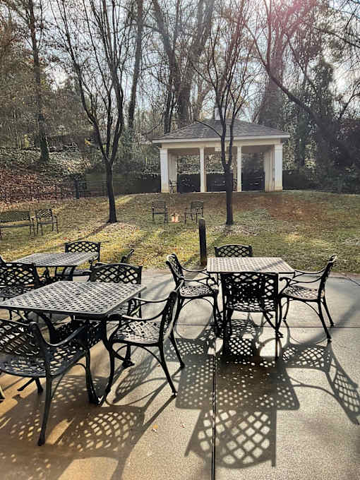 A gazebo is behind a table and chairs.