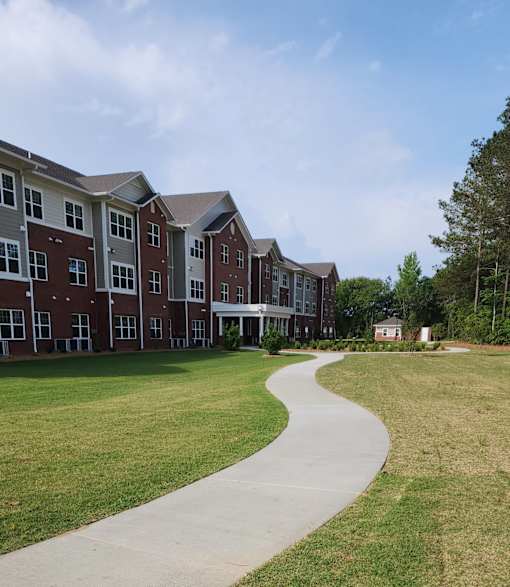 A long building with a green lawn in front.