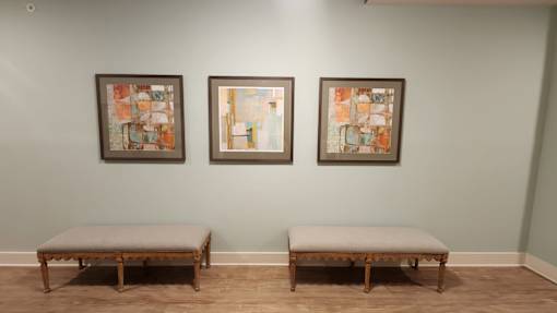 Three framed artworks hang on a wall above two benches.