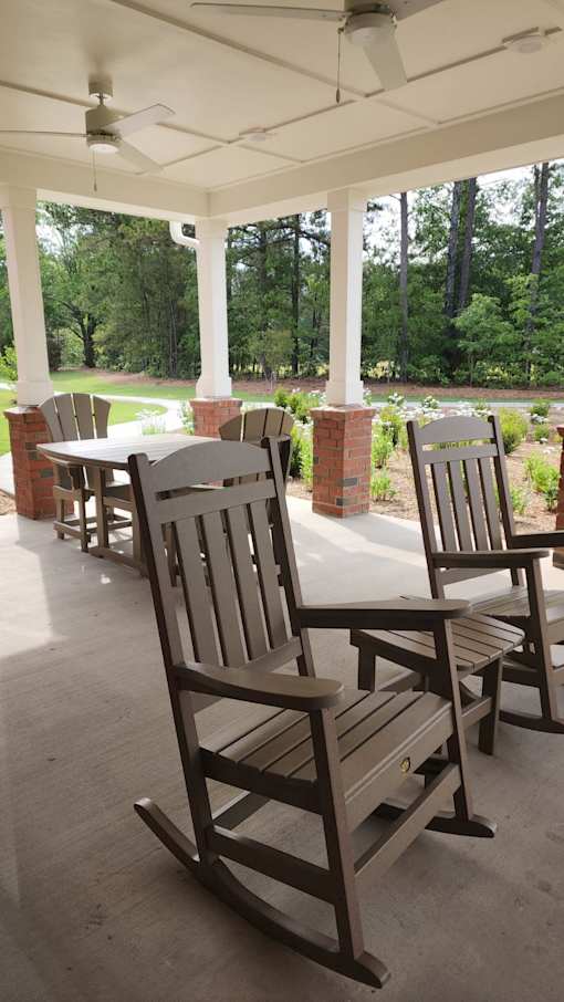 A porch with rocking chairs and a ceiling fan.