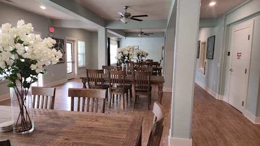 A room with a table and chairs and a vase of flowers.
