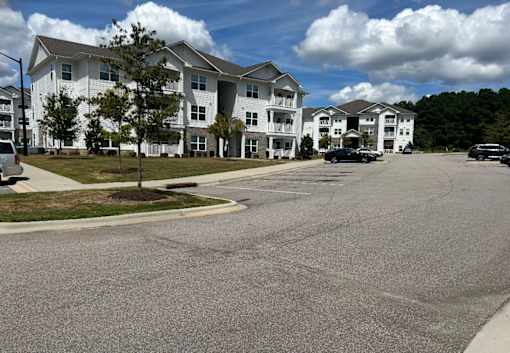 A large white building with a parking lot in front.