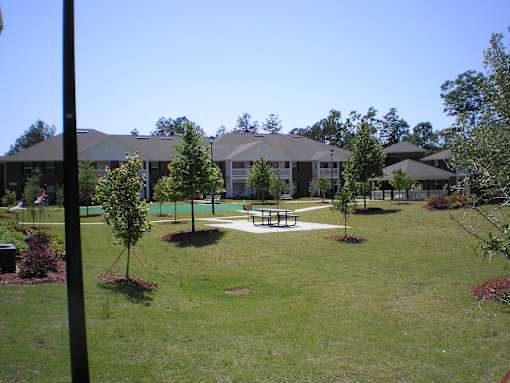 A grassy area with a picnic table and trees in front of a building.