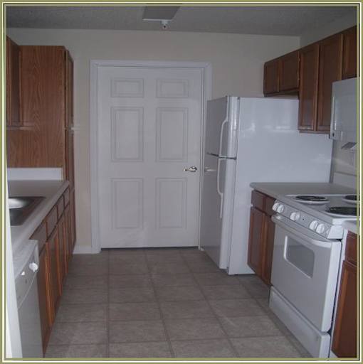 A kitchen with white appliances and brown cabinets.