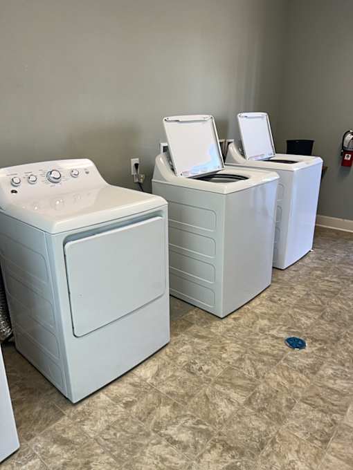 Three white front loading washing machines in a laundry room.
