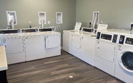 A row of white front load washing machines in a laundromat.
