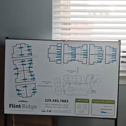 A sign for Flint Ridge Apartments shows the layout of the buildings and the lease up status.